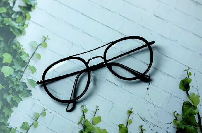 a pair of glasses laying on top of a white brick wall